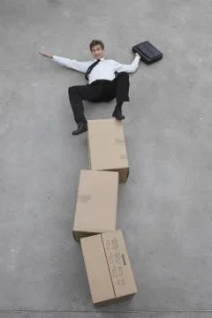 Businessman balancing on stack of cardboard boxes, portrait, elevated view Stock Photos