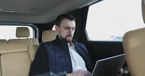 Businessman with a beard working on a laptop while traveling on backseat of a ca Stock Footage 86091737