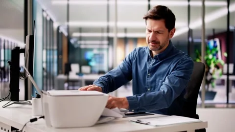 Businessman Bend Down To Remove Paper Stuck In Printer Stock Footage 274372203