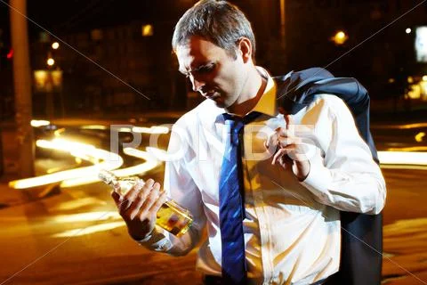 A businessman with a bottle of whisky at night Stock Photos