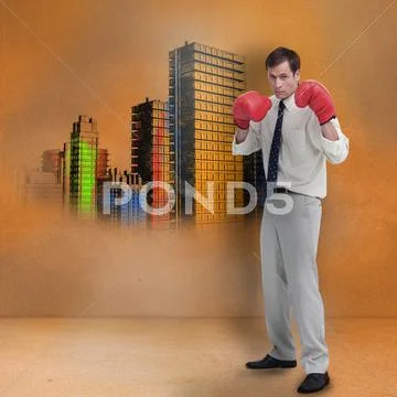 Businessman with boxing gloves standing in front of colored city Stock Photos