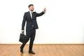 The businessman with a briefcase gesturing on the white wall background Photo