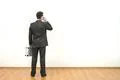 The businessman with a briefcase phones on the white wall background Photo