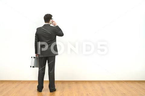 The businessman with a briefcase phones on the white wall background Stock Photos