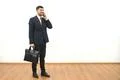The businessman with a briefcase phones on the white wall background Photo