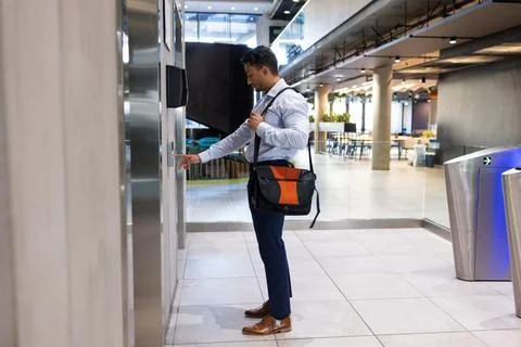Businessman with briefcase pressing elevator button in modern office building Foto stock