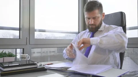 Businessman browsing document, in ring binder talking by smartphone, office 库存影片 73169892