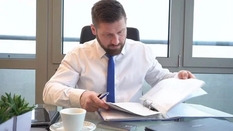 Businessman browsing documents, making notes in ring binder in office, portrait 库存影片 72500507