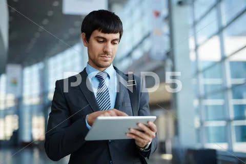 Businessman browsing in his touchpad in office center Stock Photos