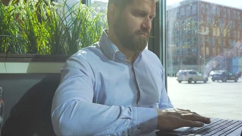 Businessman browsing laptop, looking at camera, cafe, close profile steadicam 库存影片 73299799