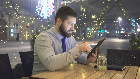 Businessman browsing tablet computer, evening, cafe, slider dolly shot 库存影片 72998978
