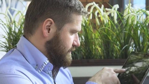 Businessman browsing tablet computer, profile, in cafe, very close steadicam 库存影片 73333319
