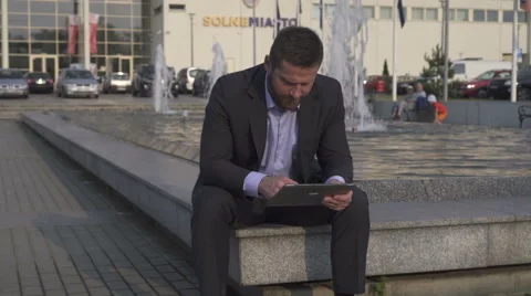 Businessman browsing tablet, sitting on wall. 库存影片 52754860