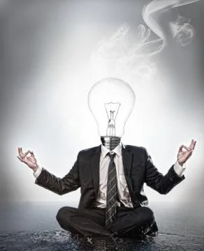 Businessman with bulb head sitting in meditation position Stock Photos