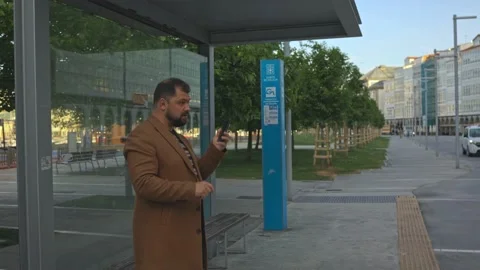 A businessman at a bus stop makes a call on a mobile phone, solves cases Stock Footage 220320945