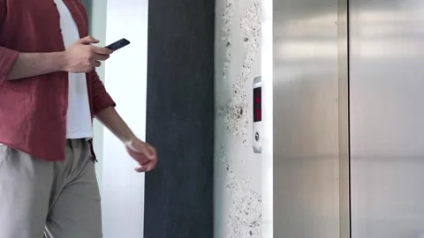 Businessman calling the elevator using a phone in a modern office building.  Stock Footage 311623407
