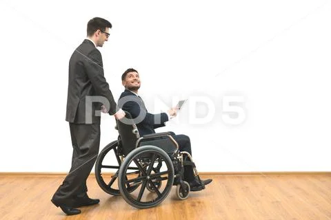 The businessman carrying a wheelchair with a disabled on a white wall backgro Stock Photos