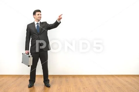 The businessman with a case gesturing on the white wall background Stock Photos
