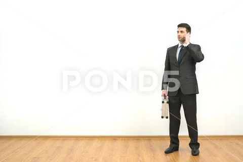 The businessman with a case phones on the white wall background Stock Photos