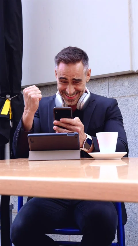 Businessman celebrating success while using smartphone and tablet.Vertical Stock Footage 301632461