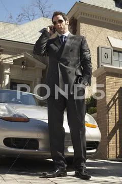 Businessman With Cellular Phone In Driveway