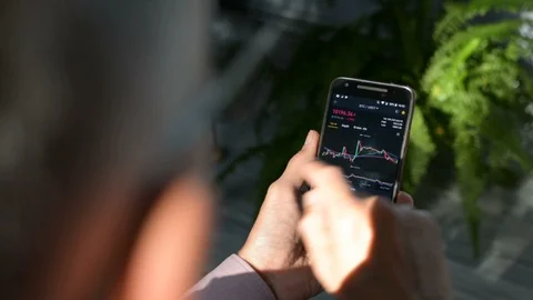 Businessman is checking Bitcoin price chart on crypto exchange on amobile phone 스톡 동영상 114985502