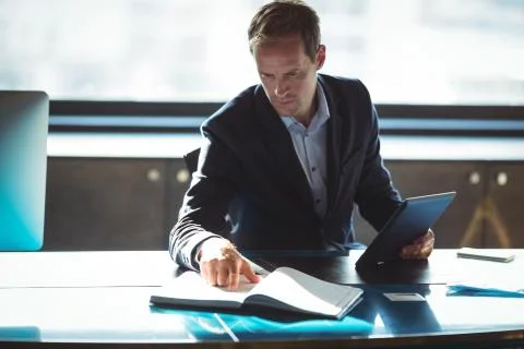 Businessman checking his diary while using digital tablet Stock Photos