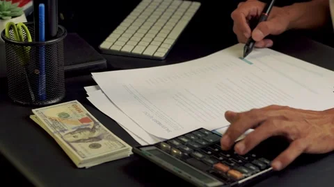 A businessman is checking income on a document using a calculator. business.. Stock Footage 308876565