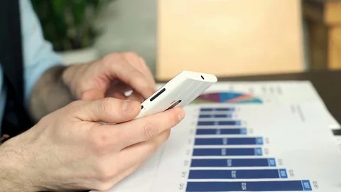 Businessman checking results on graphs and comparing them with information on sm Stock-Footage 73302070