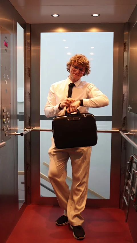 Businessman checks watch in elevator feeling late Stock Footage 333511654