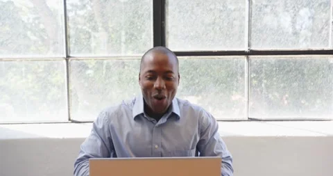 Businessman clapping hands and smiling while working on laptop by window Stock Footage 346285380