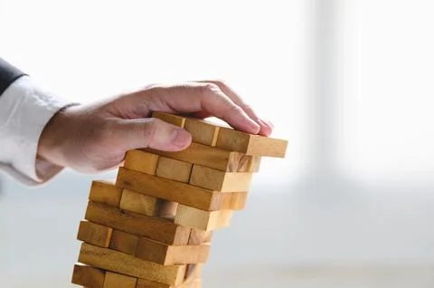 Businessman collapsing stacked tower wood block by hand as failure or bankr.. Stock Photos