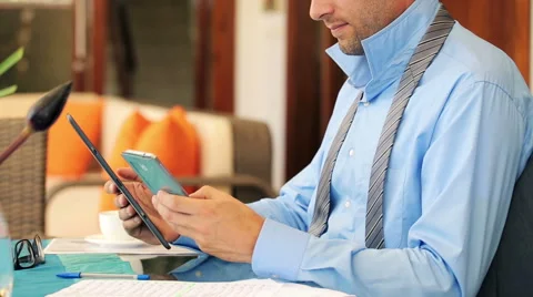 Businessman comparing data on smartphone and tablet by table at home HD Stock Footage 40881312