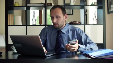 Businessman comparing data on smartphone and laptop in the office HD Stock Footage 45677409