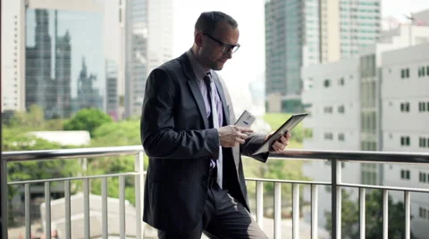 Businessman comparing data on smartphone and tablet computer on terrace  HD Stock Footage 51432539