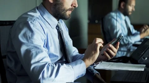 Businessman comparing data on smartphone, laptop and documents sitting in office Stock Footage 69884962