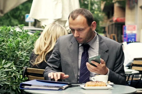 Businessman comparing data on smartphone, tablet computer sitting in cafe NTSC Stock Footage 43338823