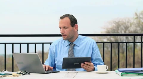 Businessman comparing data on tablet and laptop on terrace HD Stock Footage 41966908