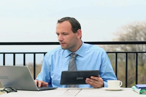 Businessman comparing data on tablet and laptop on terrace NTSC Stock Footage 41966935