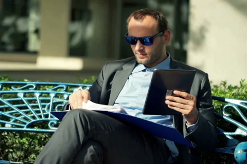 Businessman comparing data on tablet and documents in the city NTSC Stock Footage 44240769