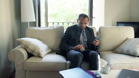 Businessman comparing data on tablet computer and smartphone at home HD Stock Footage 46216282