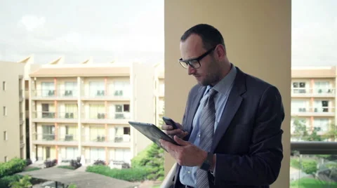 Businessman comparing data on tablet computer and smartphone on terrace HD Stock Footage 48704961