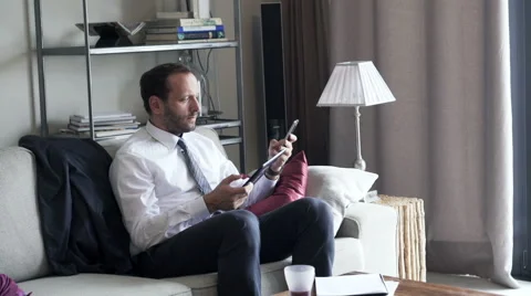 Businessman comparing data on tablet computer and smartphone at home Stock Footage 58988855