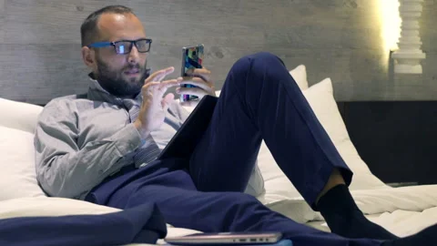 Businessman comparing data on tablet computer and smartphone on bed Stock Footage 86597227