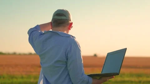 Businessman with computer in hands works in wheat field, checking harvest Stock Footage 319210759