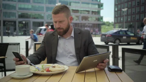 Businessman copy data from tablet to smartphone, during lunch, steadicam. Vidéo 66331510