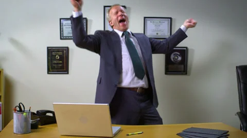Businessman dancing excitedly at his desk in his office Stock Footage