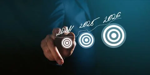 Businessman on dark background using digital pie chart and target Stock Photos