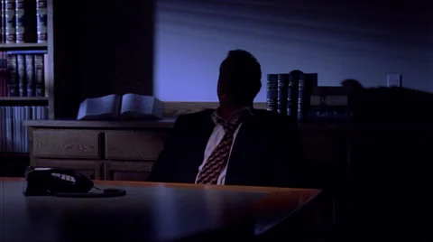 Businessman in a darkened room, looking thoughtful and serious Stock Footage 59240296