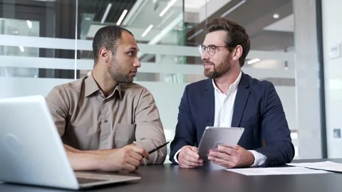 Businessman discussing with colleague at workplace using digital tablet  Vídeo Stock 338058564